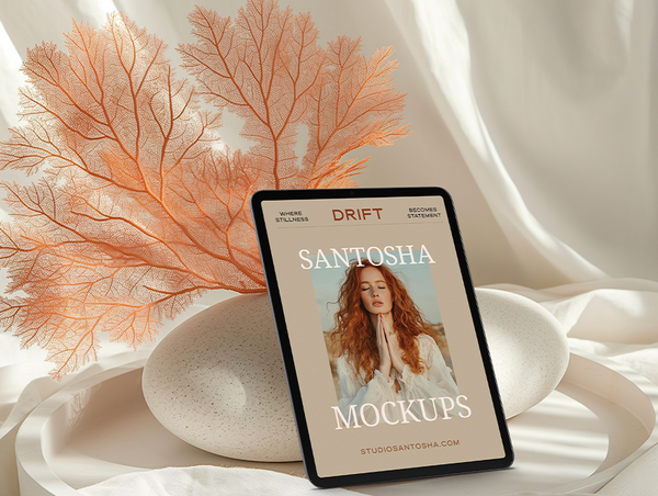 iPad mockup from the DRIFT Collection by Studio Santosha, showing a woman’s portrait cover design with coral and stone accents on a soft fabric background.
