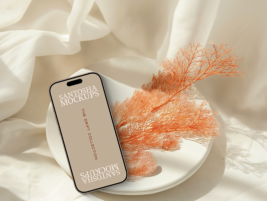 iPhone mockup from the DRIFT Collection by Studio Santosha, displayed on a white dish with coral decoration and soft fabric backdrop.
