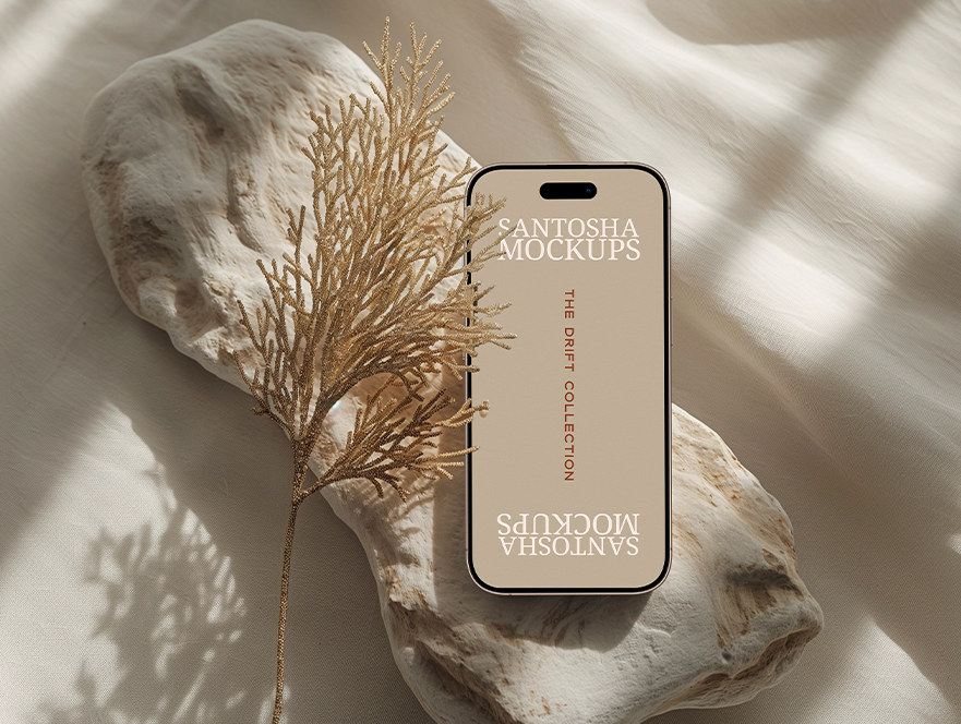 iPhone mockup from the DRIFT Collection by Studio Santosha, displayed on a textured stone surface with golden coral decoration and soft fabric backdrop.