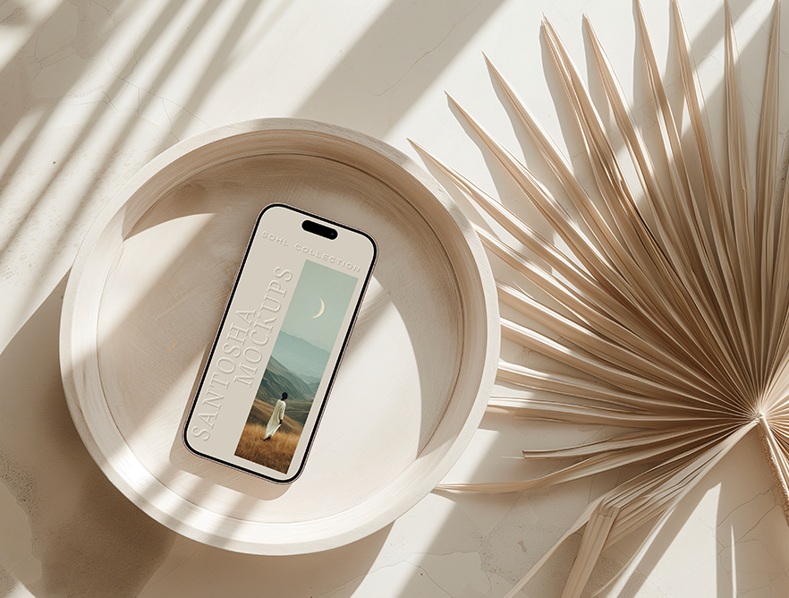 iPhone mockup from the SOHL Collection by Studio Santosha — styled on a round neutral tray with a dried palm frond, bathed in warm natural sunlight.