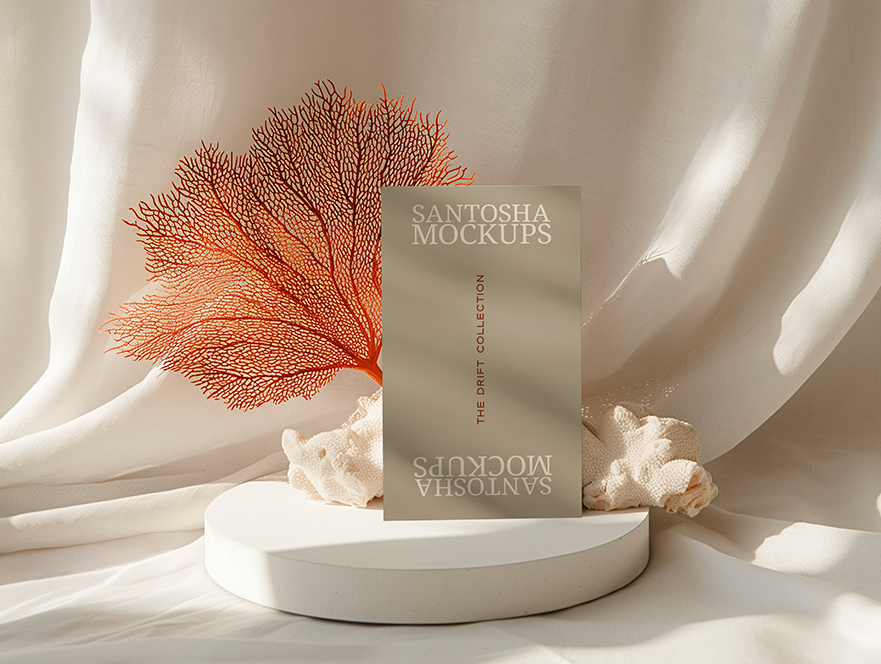 Vertical business card mockup from the DRIFT Collection by Studio Santosha, displayed on a white pedestal with coral decoration and soft fabric backdrop.